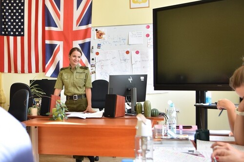  Lektorka języka angielskiego na tle flag. Po prawej stronie ekran interaktywny