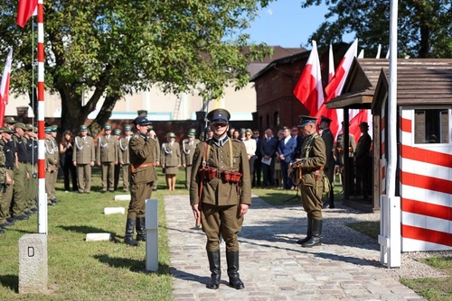 Pokaz Grupy Rekonstrukcyjnej Centralnej Szkoły Podoficerskiej Korpusu Ochrony Pogranicza w Osowcu. W tle uczestnicy i goście podczas otwarcia repliki przejścia granicznego. 