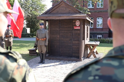 Funkcjonariusz w historycznym mundurze stoi przed posterunkiem K.O.P. 