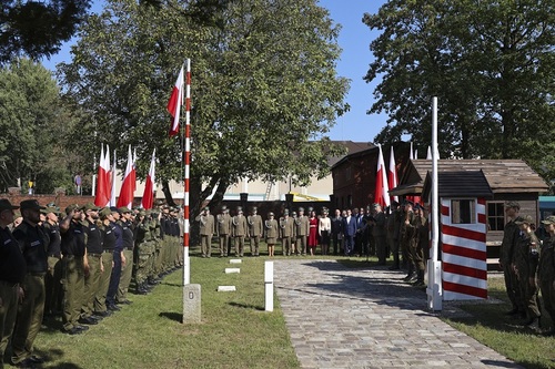 Uczestnicy wydarzenia stoją na baczność podczas odgrywania hymnu państwowego. 