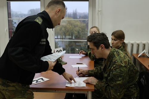 Przedstawiciel SG i funkcjonariusz pochyleni nad arkuszem egzaminacyjnym Przedstawiciel SG i funkcjonariusz pochyleni nad arkuszem egzaminacyjnym