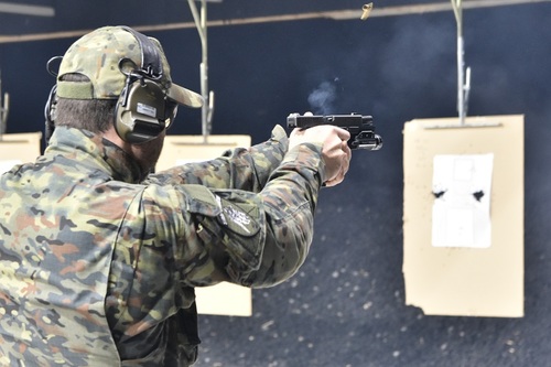 Funkcjonariusz SG trzyma w dłoniach pistolet tuż po oddaniu strzału Funkcjonariusz SG trzyma w dłoniach pistolet tuż po oddaniu strzału